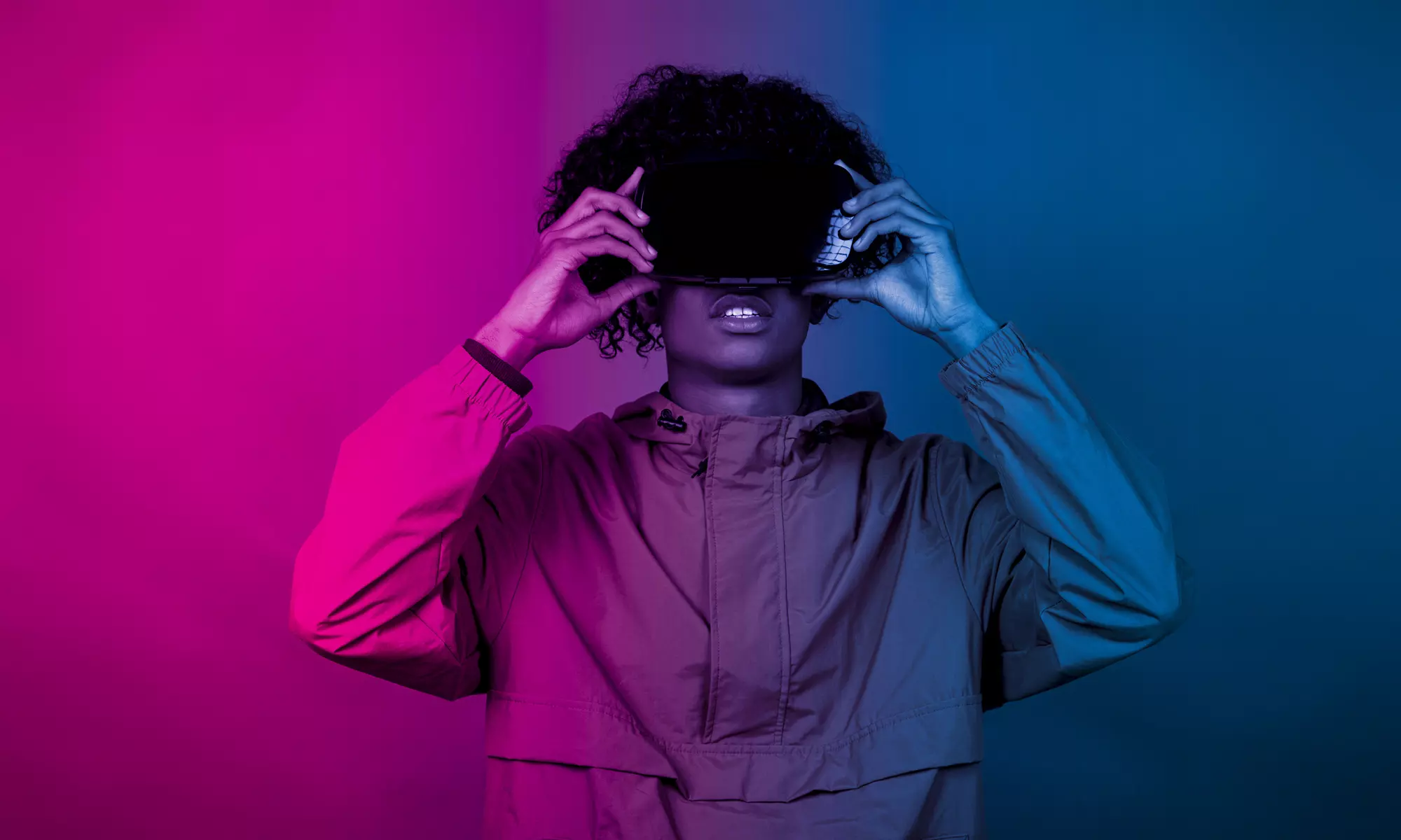 A young African male with VR glasses standing under the blue and purple lights